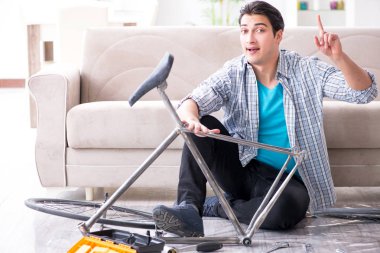 Evde bisiklet tamir eden genç bir adam.