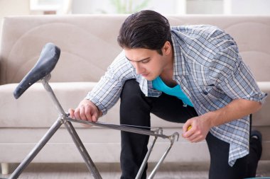 Evde bisiklet tamir eden genç bir adam.