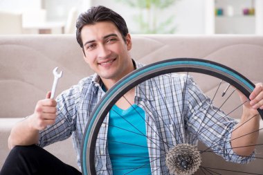 Evde bisiklet tamir eden genç bir adam.