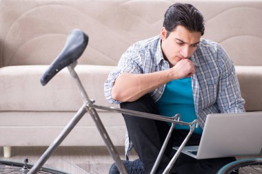 Evde bisiklet tamir eden genç bir adam.