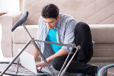 Evde bisiklet tamir eden genç bir adam.