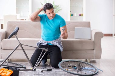 Evde bisiklet tamir eden genç bir adam.