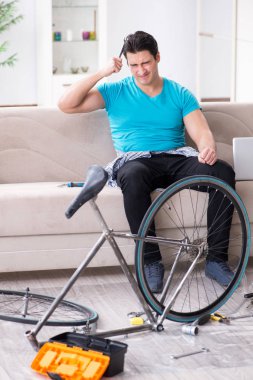 Evde bisiklet tamir eden genç bir adam.