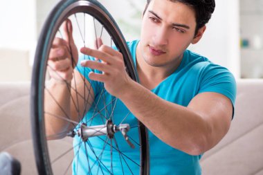 Evde bisiklet tamir eden genç bir adam.