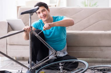 Evde bisiklet tamir eden genç bir adam.