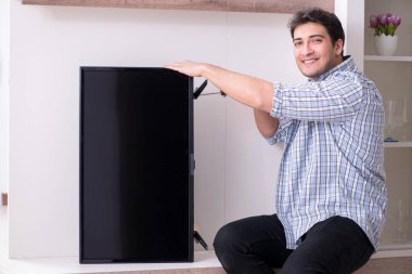 Evdeki bozuk televizyonu tamir eden adam.