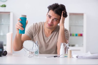 Genç yakışıklı adam aynaya bakıyor. 