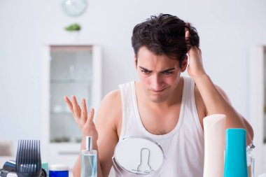 Genç yakışıklı adam aynaya bakıyor. 