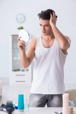 Genç yakışıklı adam aynaya bakıyor. 