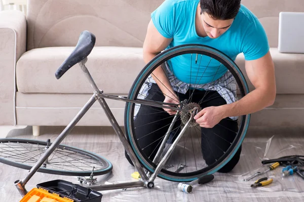 Giovane uomo che ripara la bicicletta a casa — Foto Stock