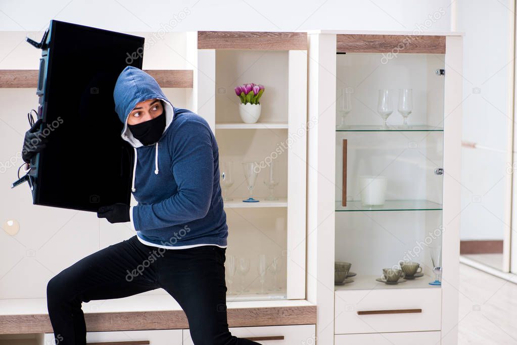 Man burglar stealing tv set from house