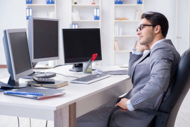 Birçok ekranın önünde oturan bir iş adamı