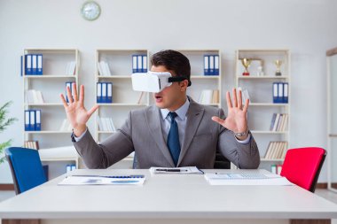 Ofiste sanal gerçeklik gözlüklü bir iş adamı var.