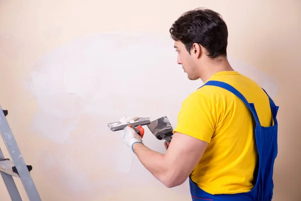 壁に石膏を適用若い請負業者の従業員 — ストック写真