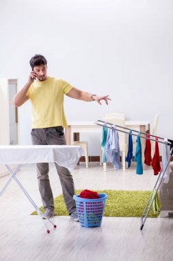 Yakışıklı koca evde kıyafet ütülüyor.