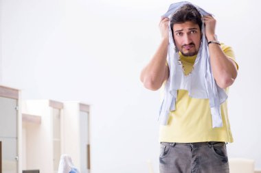 Yakışıklı koca evde kıyafet ütülüyor.