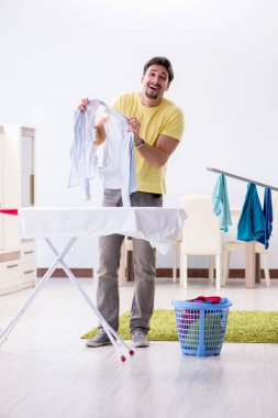 Yakışıklı koca evde kıyafet ütülüyor.