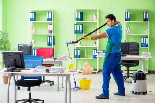 Schöner Mann putzt Büro mit Staubsauger — Stockfoto