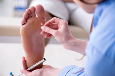 Doktor çekiçle sinir reflekslerini kontrol ediyor