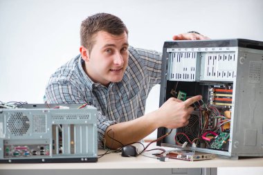 Genç teknisyen atölyede bilgisayar tamir ediyor.