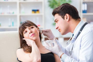Doktor muayene sırasında hastaların kulaklarını kontrol ediyor.
