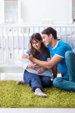 Yeni doğmuş bebekleriyle halıda oturan genç ebeveynler. 