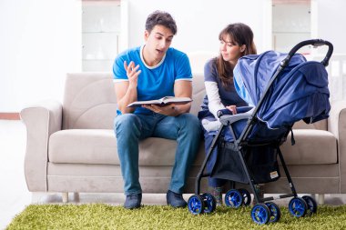 Bebekleri bebek arabasında oturan genç ebeveynler.