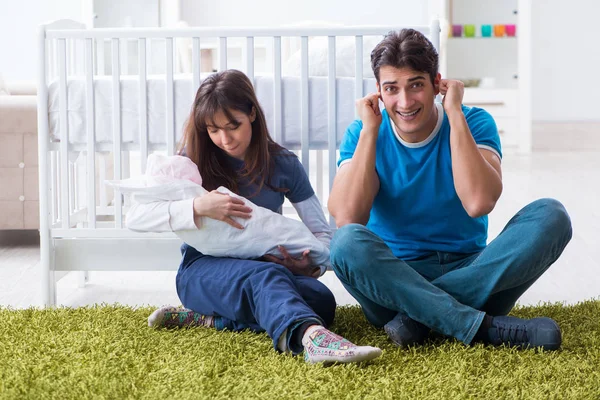 Jonge ouders met hun pasgeboren baby zittend op het tapijt — Stockfoto