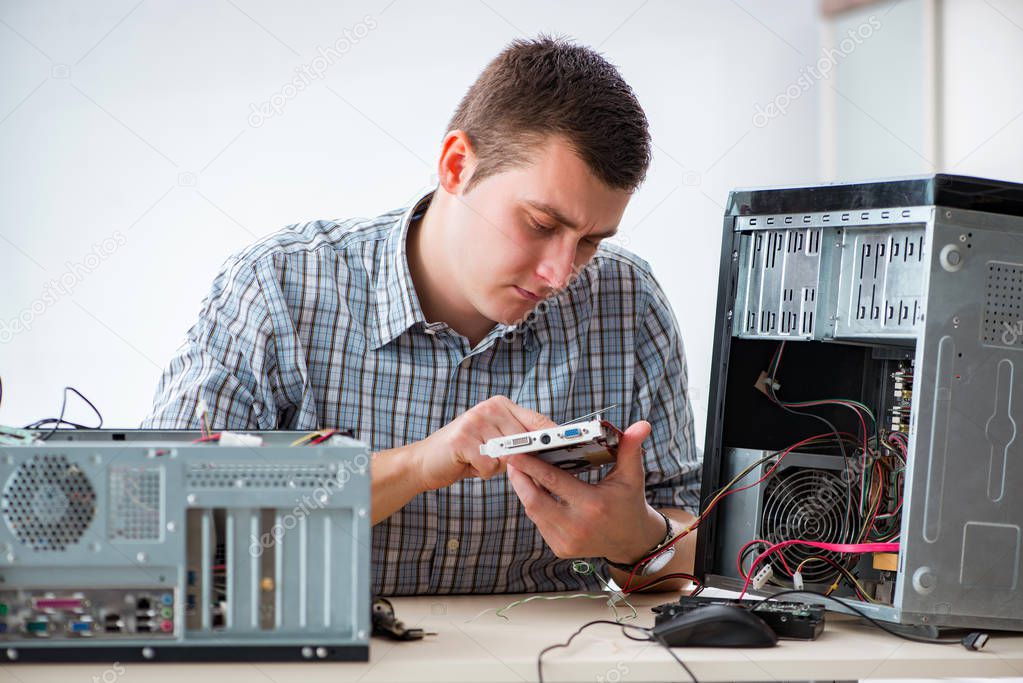 Young technician repairing computer in workshop