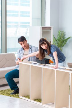 Yeni evde mobilya montajı yapan genç bir aile.