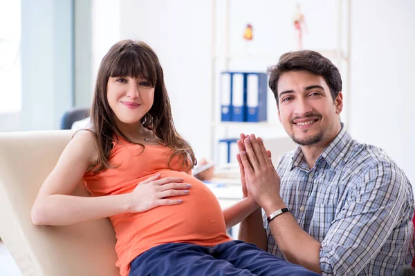 Hamile kadın kocasıyla klinikteki doktoru ziyaret ediyor. — Stok fotoğraf