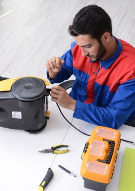 Servis merkezinde elektrik süpürgesini tamir eden adam.