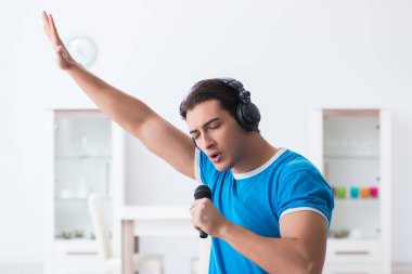 Genç yakışıklı adam evde karaoke yapıyor. 