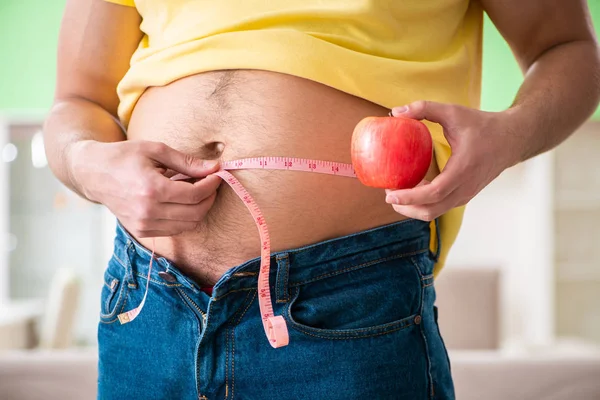 Hombre midiendo grasa corporal con cinta métrica en concepto de dieta — Foto de Stock