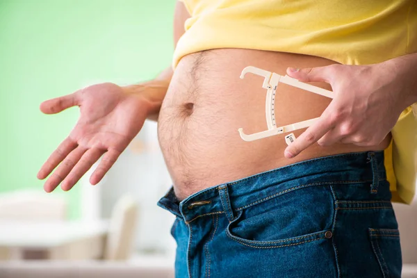 Молодой человек измеряет жир с помощью суппортов — стоковое фото