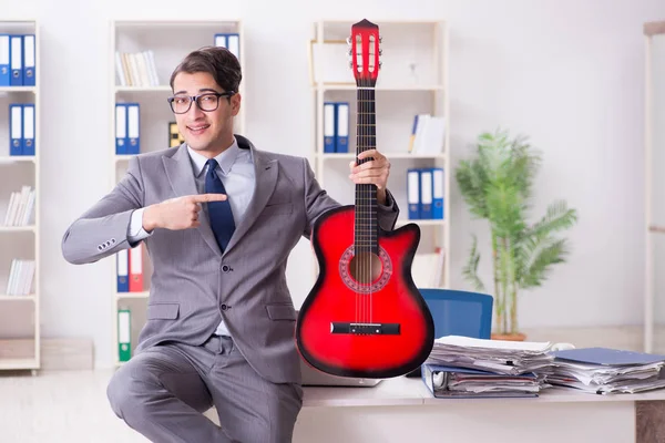 Joven hombre de negocios guapo tocando la guitarra en la oficina — Foto de Stock