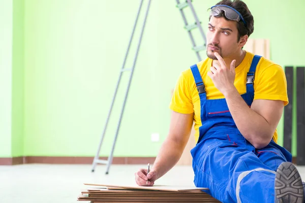 Empreiteiro profissional que coloca piso em casa — Fotografia de Stock