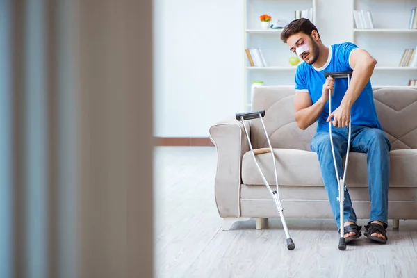 Injured man with crutches recovering at home — Stock Photo, Image