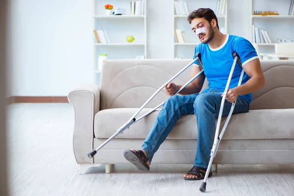 Homem ferido com muletas se recuperando em casa — Fotografia de Stock