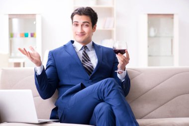 İş adamı evde oturmuş şarap içiyor.
