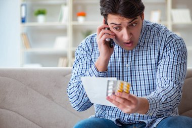 Kanepede ilaç ve reçeteyle oturan genç adam. 