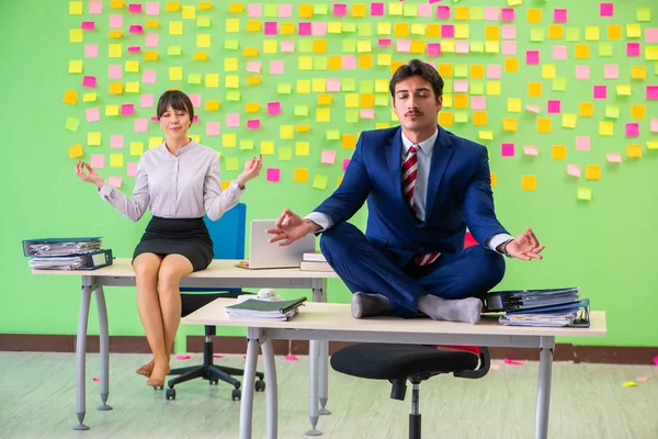 Mann og kvinne på kontoret med mange motstridende prioriteringer i – stockfoto