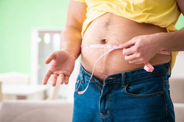 Hombre midiendo grasa corporal con cinta métrica en concepto de dieta —  Fotos de Stock