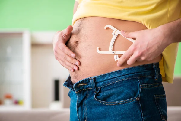 Joven midiendo grasa corporal con pinzas — Foto de Stock