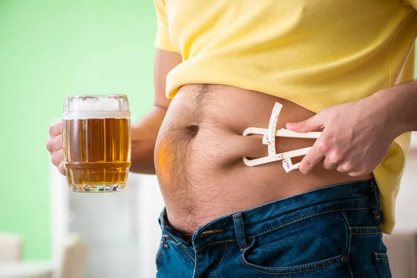 肥胖男子持有啤酒在节食的概念 — 图库照片