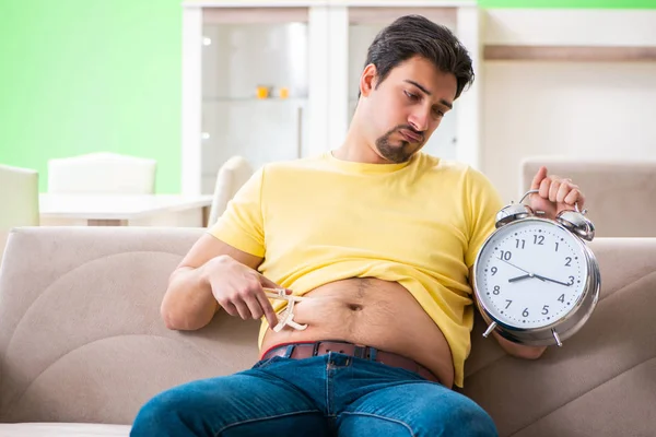 Hombre medir la grasa corporal con pinzas en el concepto de gestión del tiempo — Foto de Stock