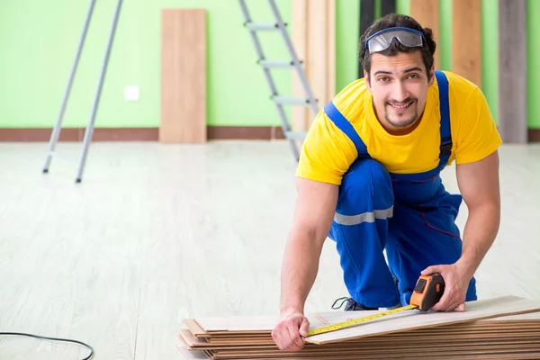 Empreiteiro profissional que coloca piso em casa — Fotografia de Stock