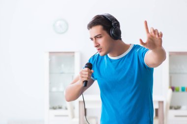 Genç yakışıklı adam evde karaoke yapıyor. 