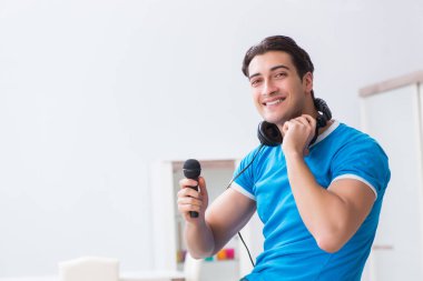 Genç yakışıklı adam evde karaoke yapıyor. 