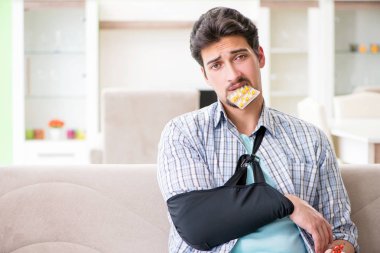 Eli yaralı genç bir öğrenci kanepede oturuyor. 